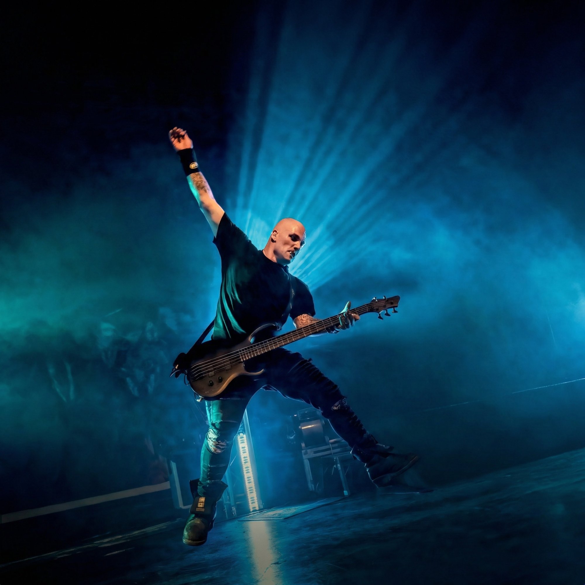 Christopher Dean performing live on stage with bass guitar under dramatic blue lighting